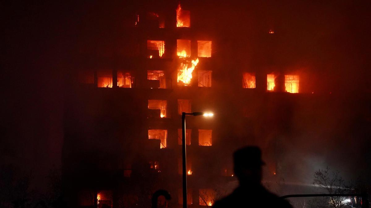 Un agente observa el edificio en llamas, en el barrio de Campanar.