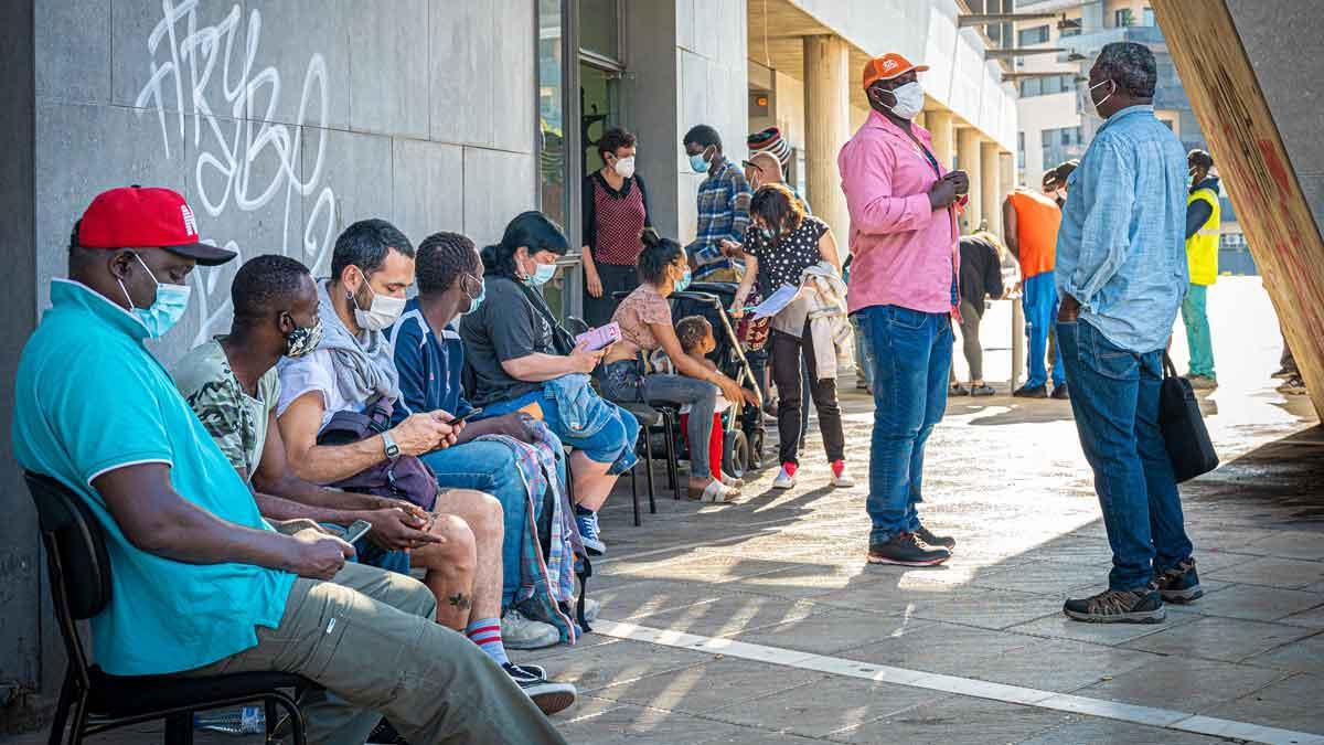 Varios hombres sin hogar esperan para recibir el pinchazo de la vacuna Janssen en Badalona.