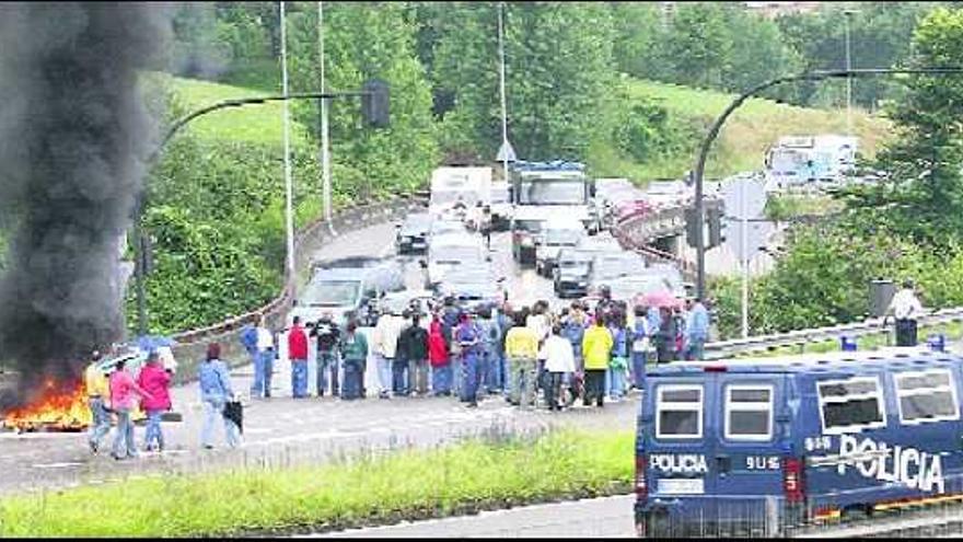 Los trabajadores de la Fábrica de Loza de San Claudio cortan el tráfico y queman neumáticos a la entrada de la autopista en Oviedo.