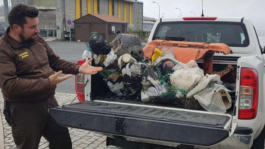 Un vigilante de A Illa muestra los plásticos retirados de una playa en la tarde de ayer. // Cedida