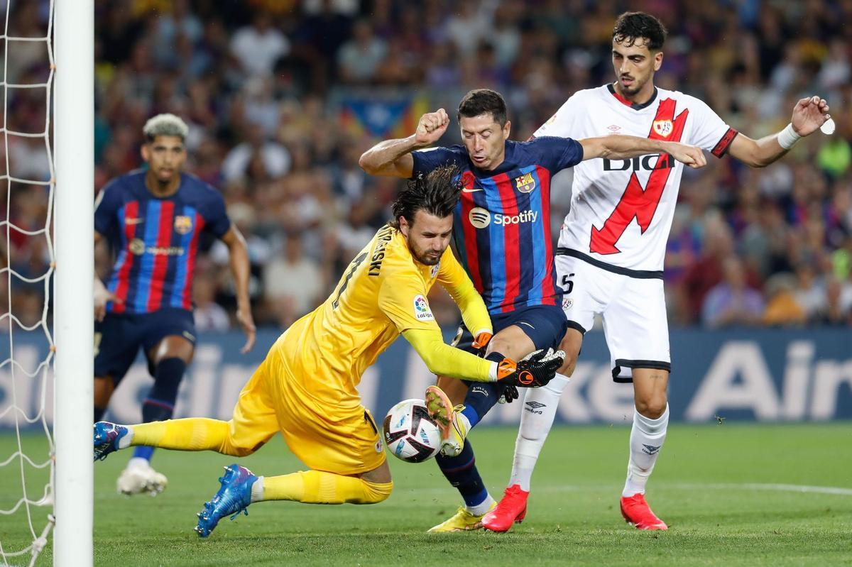 BARCELONA, 13/08/2022.- El delantero polaco del FC Barcelona Robert Lewendowski (c) lucha con el portero Stole Dimitrievski (i), del Rayo Vallecano, durante el partido correspondiente a la primera jornada de LaLiga que FC Barcelona y Rayo Vallecano disputan hoy sábado en el Camp Nou, en Barcelona. EFE/Andreu Dalmau