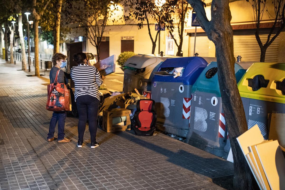 Una señora se lleva un cuadro tirado junto a unos contenedores, en una calle de Sant Andreu.