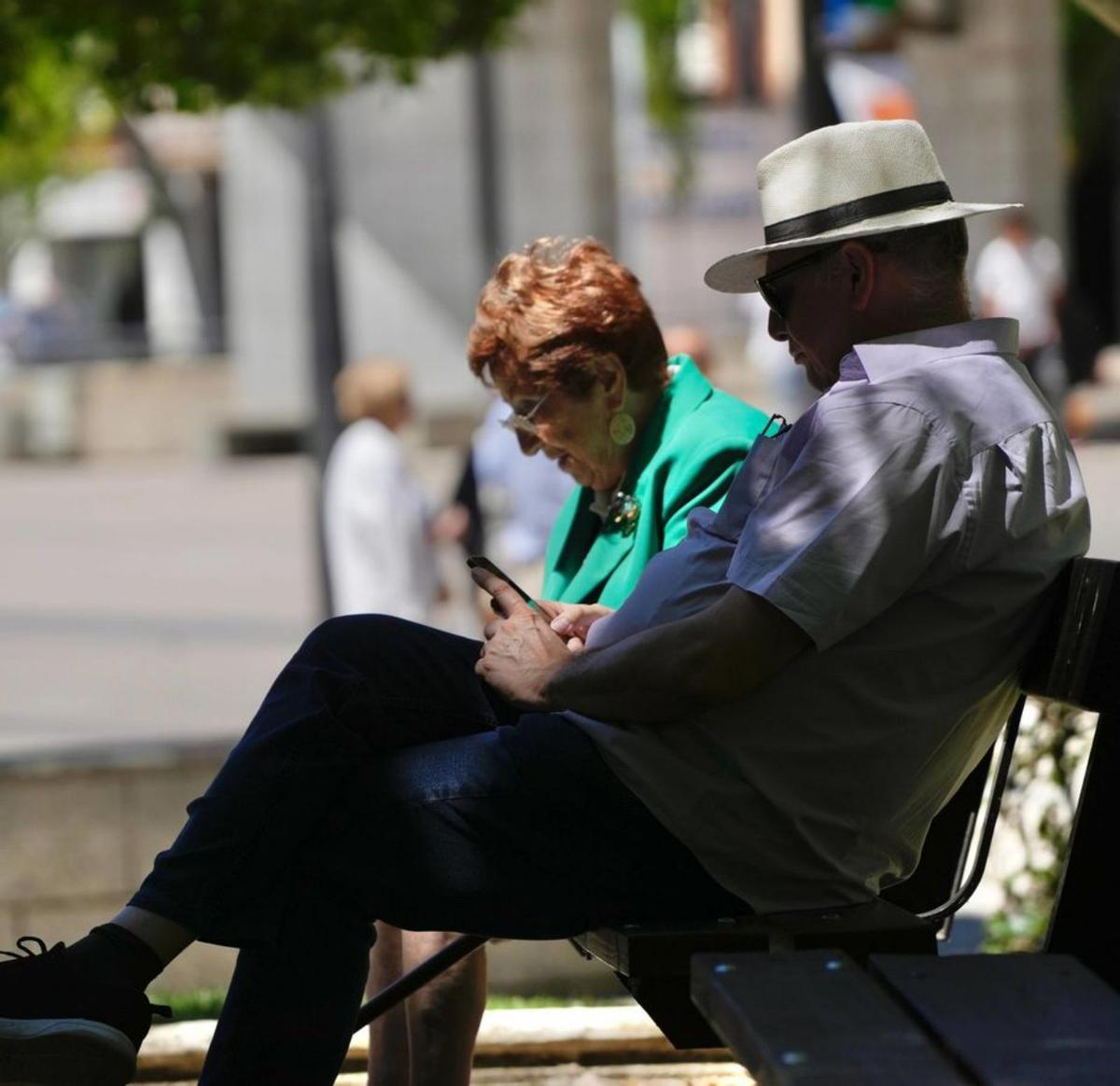 Dos personas, sentadas a la sombra en un banco. | Jose Luis Fernández