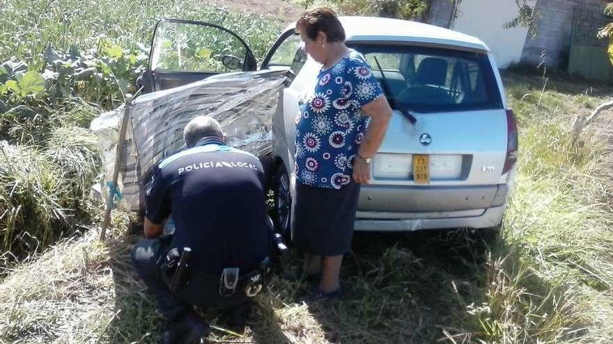 Un agente y una vecina atienden al octogenario herido en Corón. // FdV