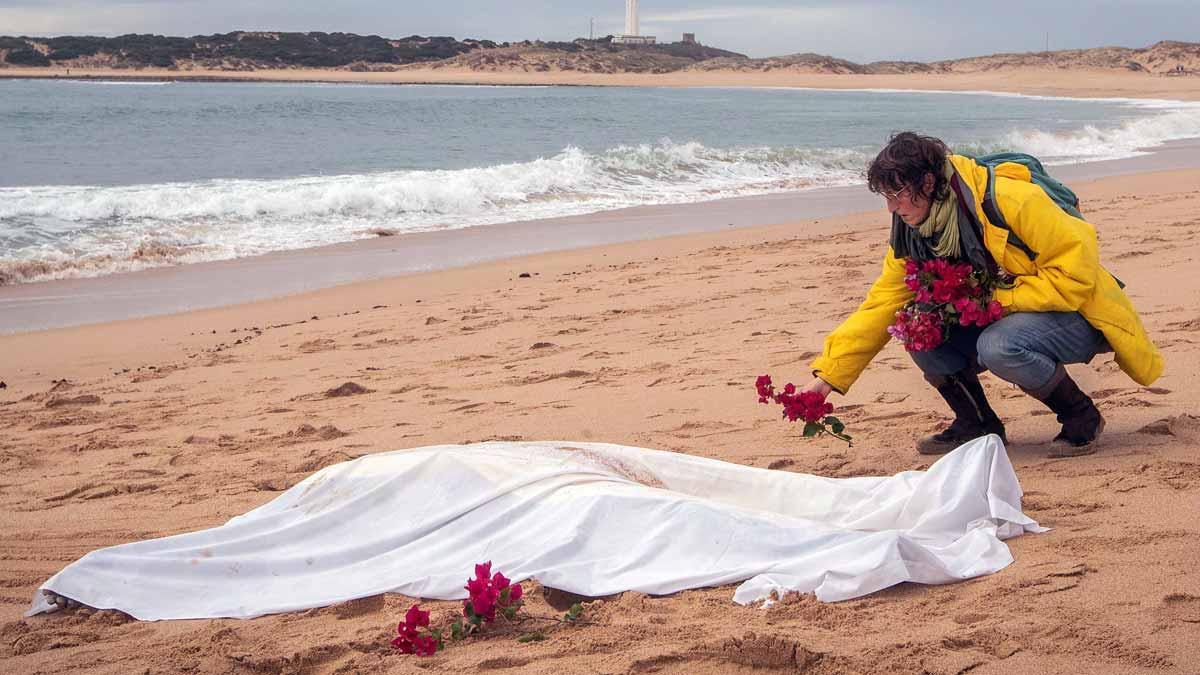 Una mujer coloca flores junto al cadáver de un migrante.