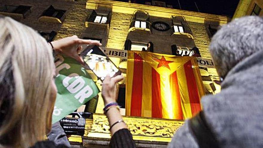 Una dona fotografia amb el mòbil una estelada gegant penjada a la façana de l&#039;ajuntament de Girona.