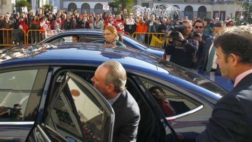 El presidente Fabra, ayer, subiendo al coche oficial para abandonar Nules y ante las protestas de trabajadores de Canal 9.