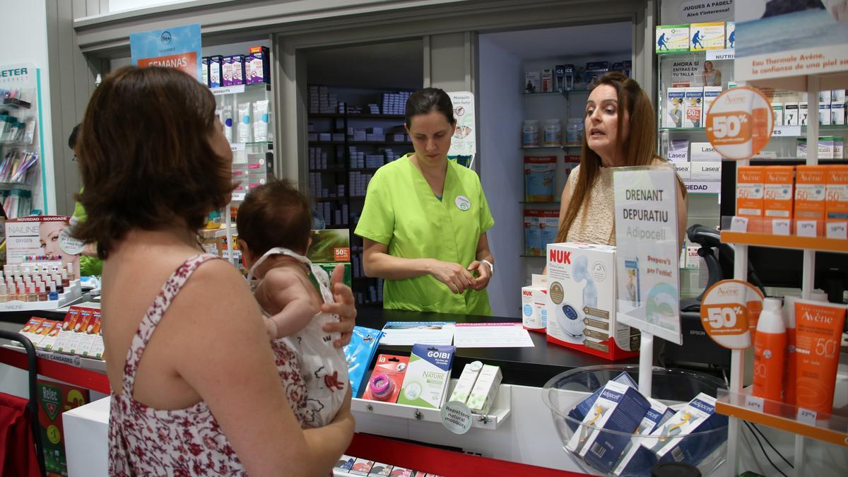 Dues professionals assessorant un mare amb el seu nadó en una farmàcia.