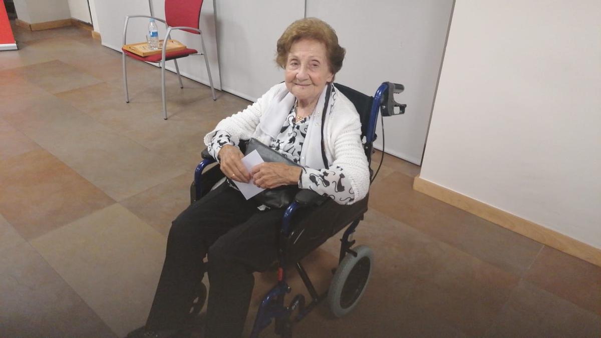 Maricuela esperando en su silla de ruedas, con el sobre para votar en la mano, en la sede del PSOE.
