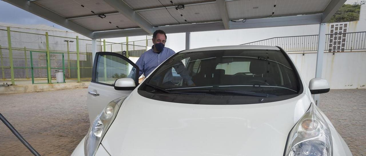 Celso Rodríguez carga su vehículo eléctrico bajo la pérgola en cuya cubierta tiene las placas fotovoltaicas.