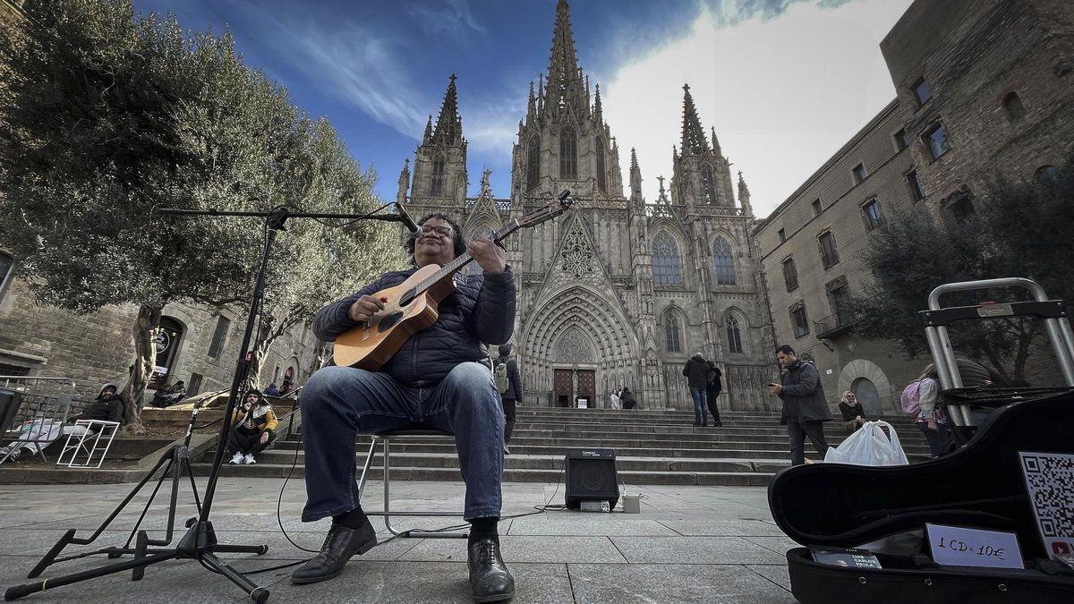 Un músico canta y toca una guitarra ante la Catedral de Barcelona.