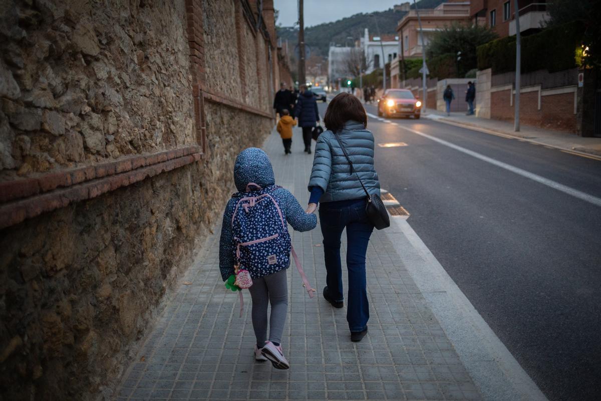 Una mujer lleva de la mano a un niño a clase.