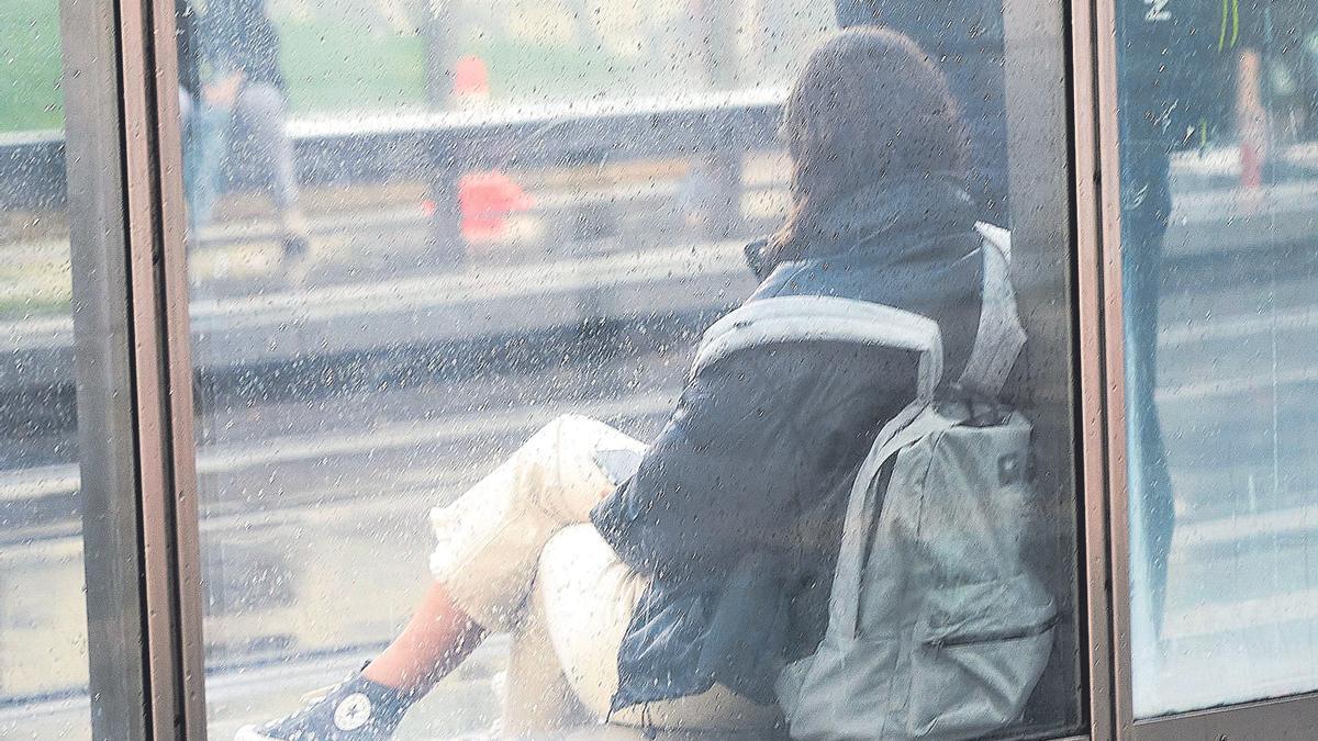 Una joven en una parada de tranvia.