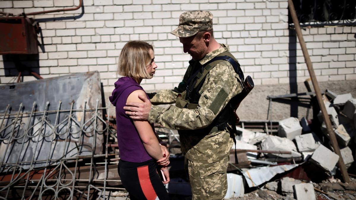 Un militar ucraniano consuela a una joven cuya casa resultó dañada por un ataque ruso en Zaporiyia.