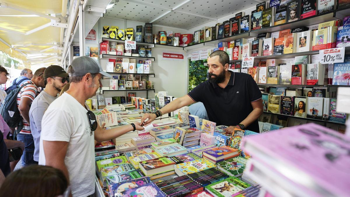 Un vendedor atiende a varios clientes en la Feria del Libro de Madrid.
