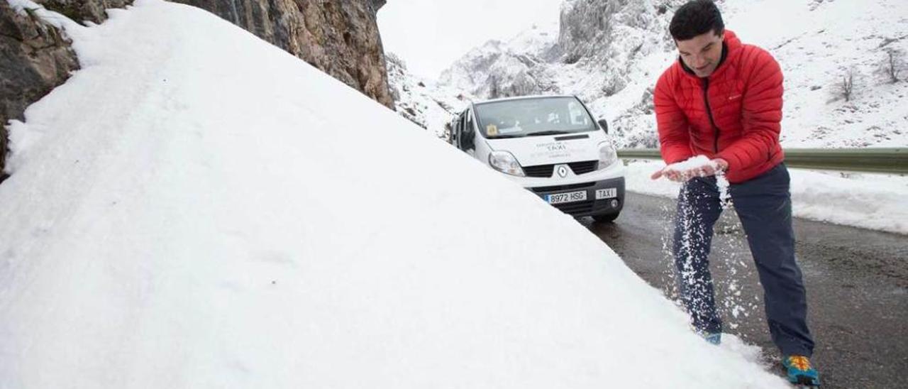 El taxista David Moradiello junto a un montón nieve caída en la carretera de acceso al pueblo. miki lópez