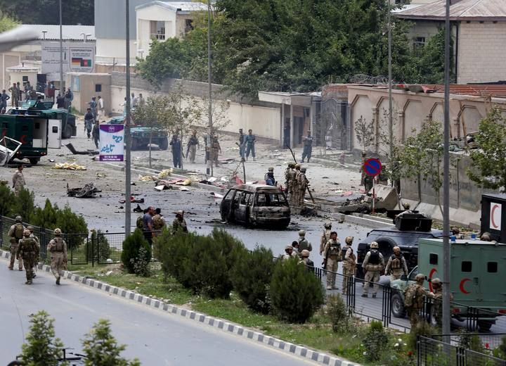 Members of security forces and police officers stand at the site of an attack near the Afghan parliament in Kabul, Afghanistan