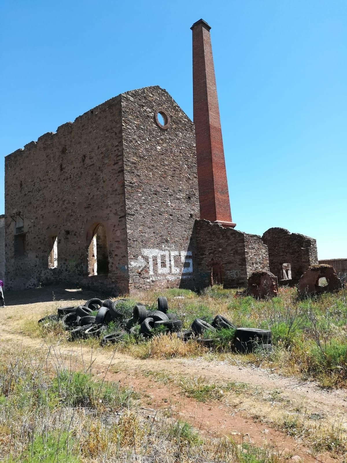 Chimenea distintiva de La Esmeralda con el vertido de neumáticos y pintadas.