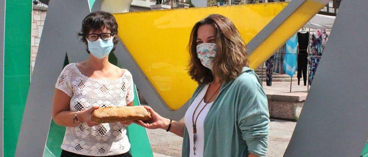 Elena Fernández Suárez y Ana Belén Marcos Álvarez sostienen una barra de pan duro delante del &quot;Culetón&quot; de Nava.