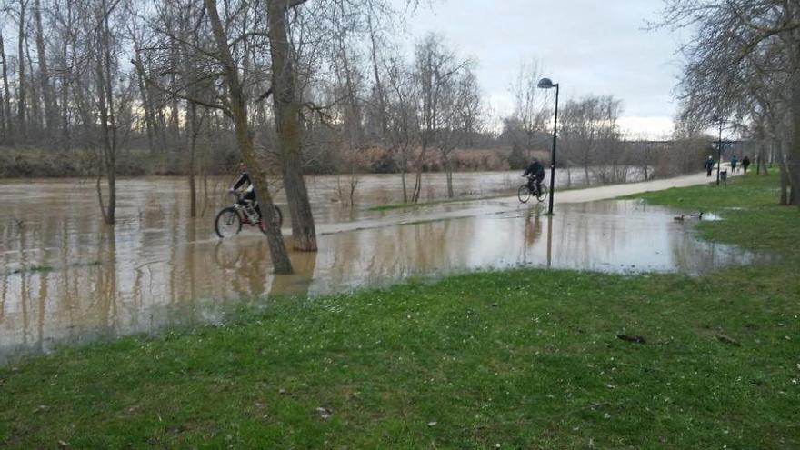 Los ciclistas circulan por el carril bici lleno de agua