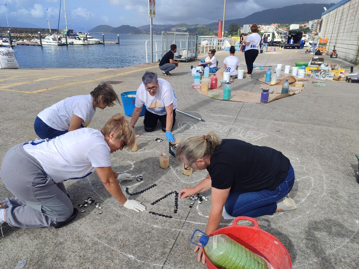 Alfombristas trabajando ayer por la tarde en la explanada de la lonja de Bueu.