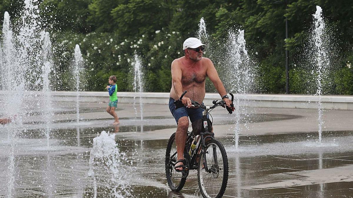 Un ciclista se refresca en las fuentes del Parc Central de València. | J.M. LÓPEZ