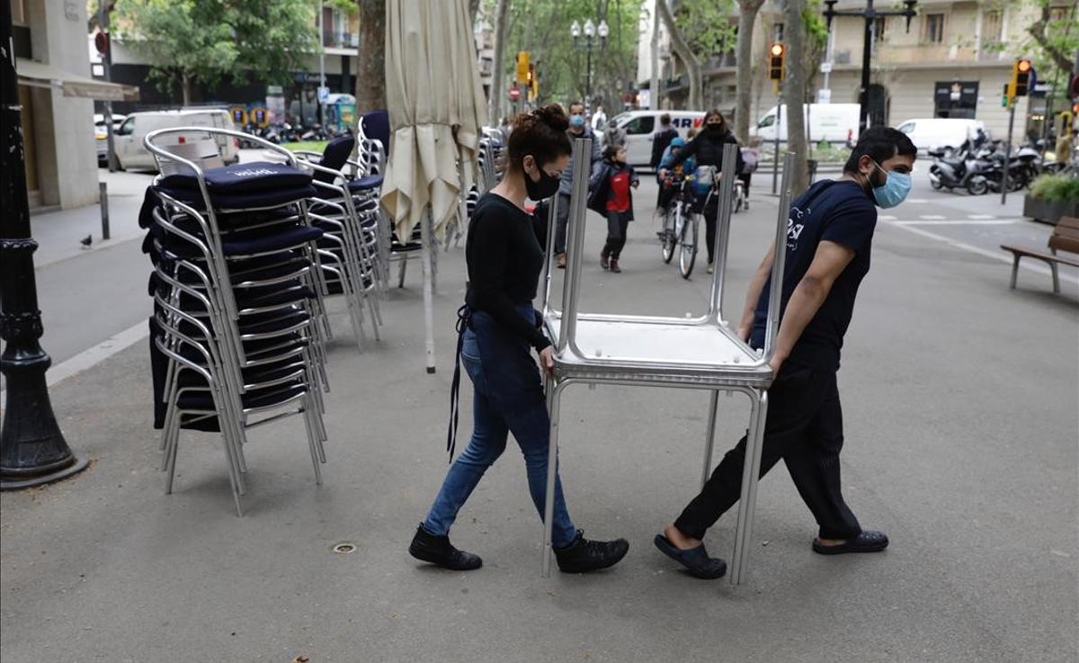 Trabajadores de un restaurante de la rambla del Poblenou, en Barcelona, recogen las mesas de la terraza a las cinco de la tarde.