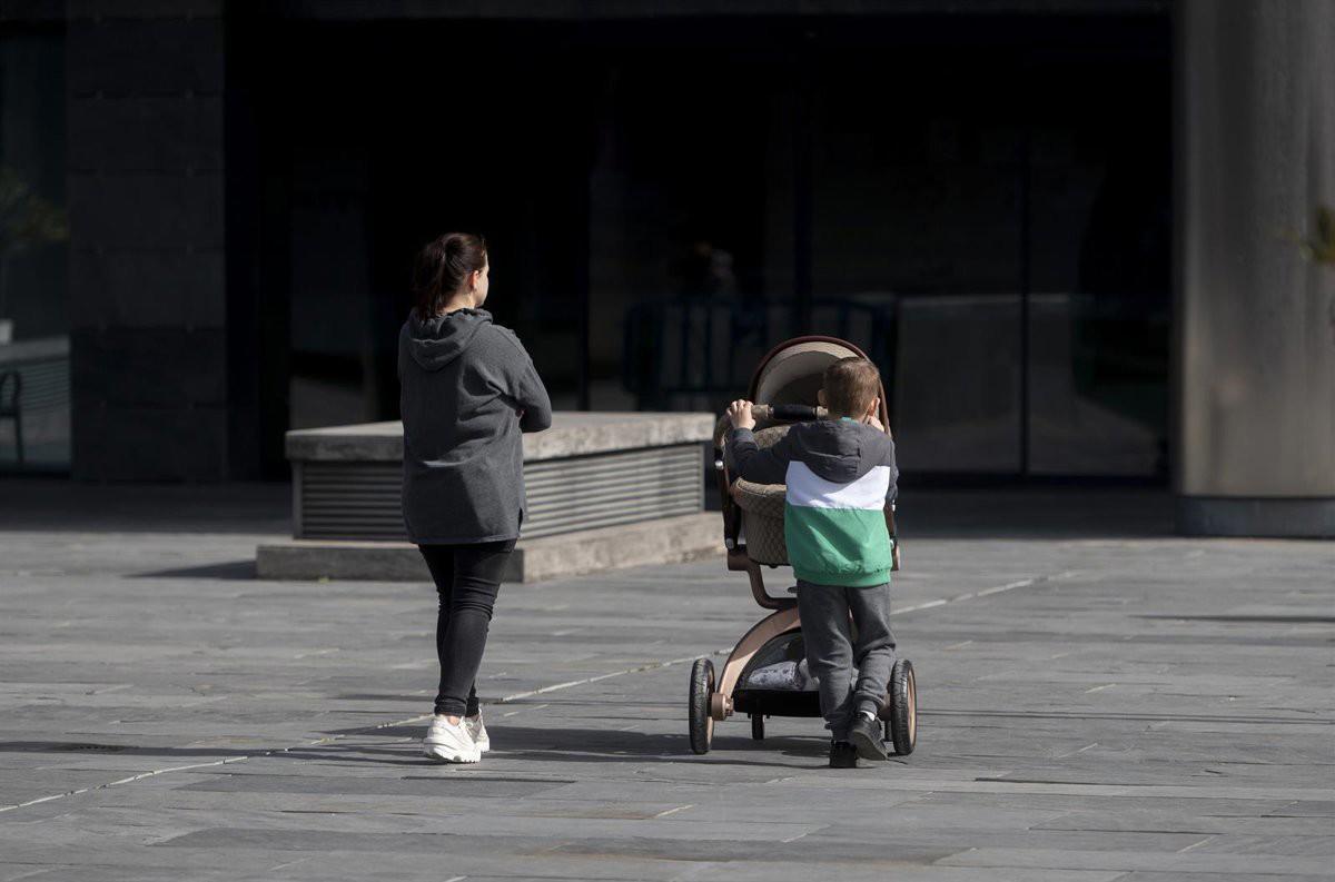 Una madre y un niño con un carro de un bebe en una imagen de archivo.