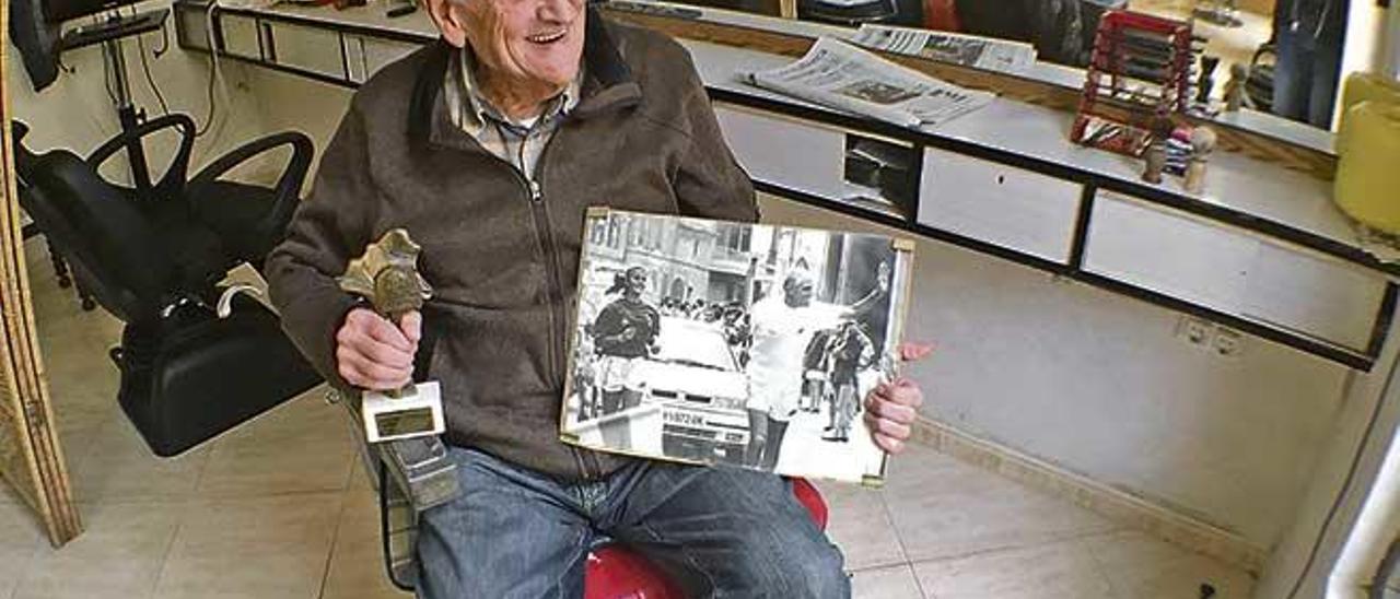 Mateu Morlà sentado en su silla de barbero de la calle Santa Catalina de Vilafranca, junto a sus recuerdos como atleta.