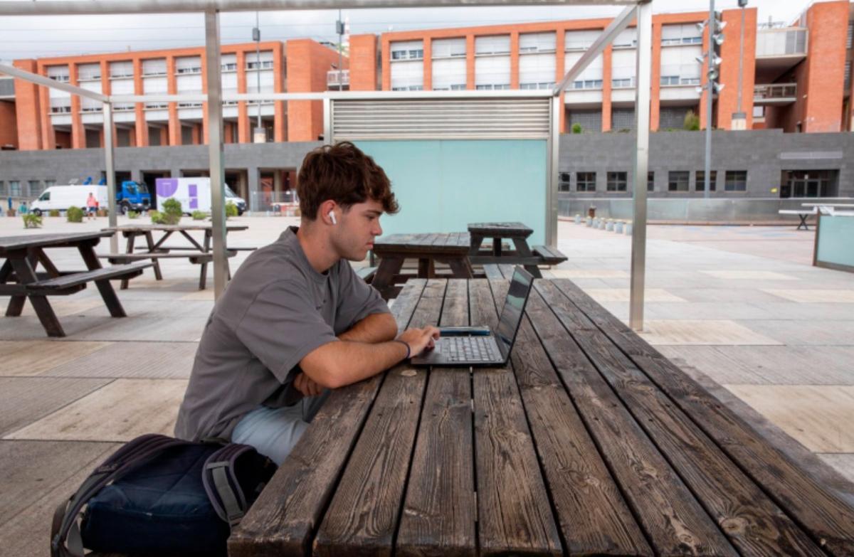 Un estudiante realiza unas tareas en su ordenador, en el campus.