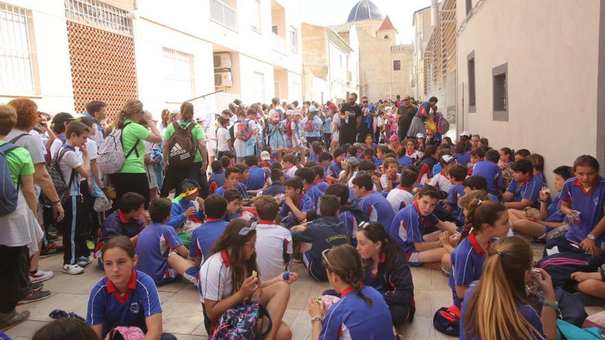 Escolares sentados en la calle que da acceso al monasterio de la Santa Faz tras llegar caminando desde Alicante.  PILAR CORTÉS