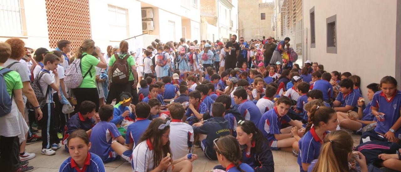 Escolares sentados en la calle que da acceso al monasterio de la Santa Faz tras llegar caminando desde Alicante.  PILAR CORTÉS