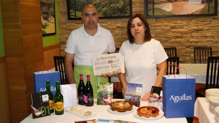 Bautista Menéndez y Teresa Lastra posan en su local con un ejemplar de LA NUEVA ESPAÑA y dos platos de fabada, entre otros productos asturianos.