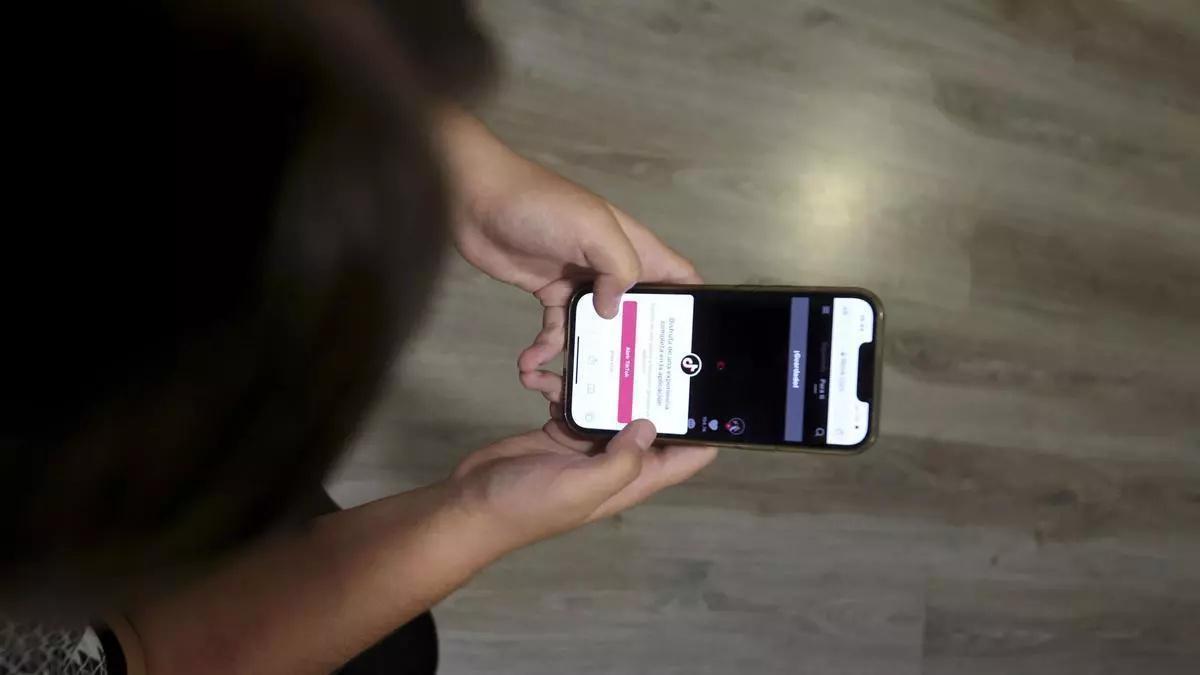 Una joven utilizando la aplicación TikTok en su teléfono móvil.