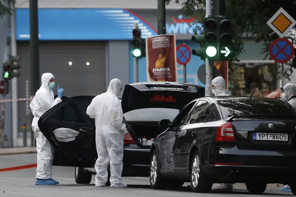 La Policía rodea el coche de Lucas Papademos tras la explosión del artefacto en el interior de su coche.