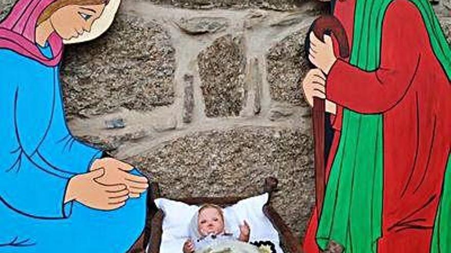 Figuras de un belén navideño en un punto de Villadepera, en el centro el mural de tela colgado en la iglesia y unas figuras dispuestas en una pequeña ventana del pueblo.