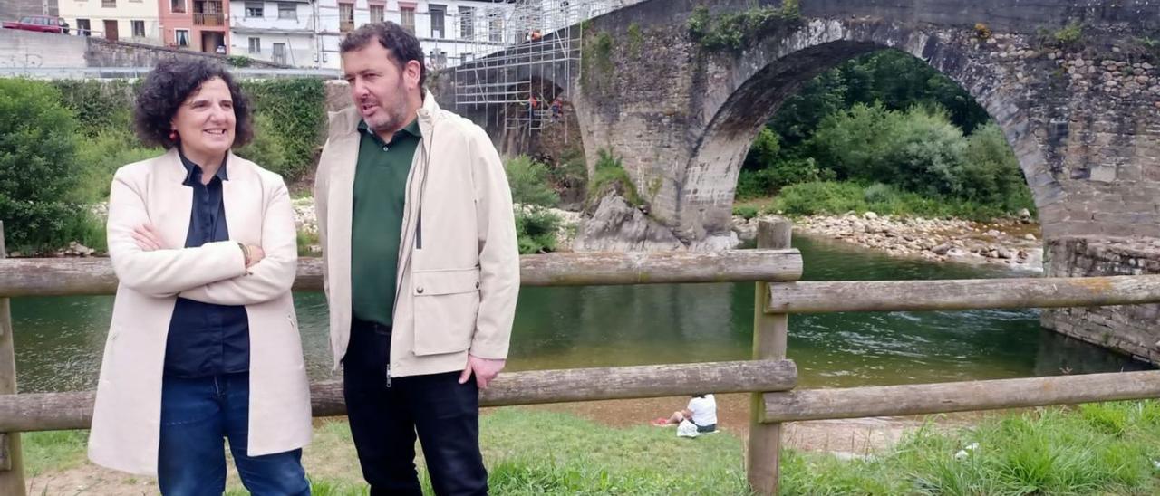 Berta Piñán y Julio García, ayer ante el paso medieval de Puente d’Arcu, con los obreros colocando andamios. | D. O.