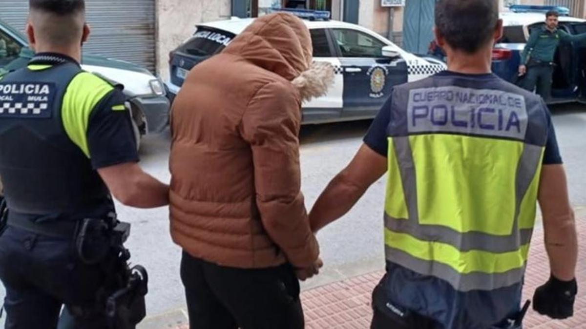 Dos agentes custodian a uno de los sospechosos del crimen, que fue detenido en Mula.