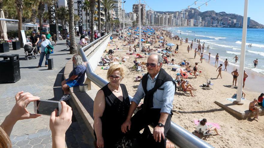 Unos turistas con su móvil en la playa de Levante