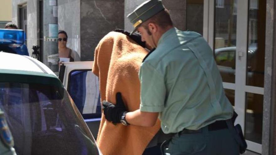 Un guardia civil conduce al detenido en Cabrales hacia el interior de un coche. / maría toraño