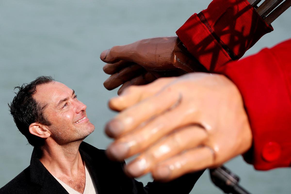 El actor Jude Law sostiene la mano de Little Amal en Folkestone, Gran Bretaña. , 19 de octubre de 2021.