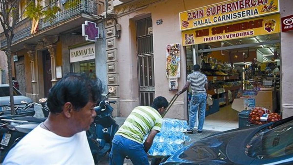 Un transportista descarga botellas de agua frente a una carnicería árabe en la calle del Roser, el lunes.