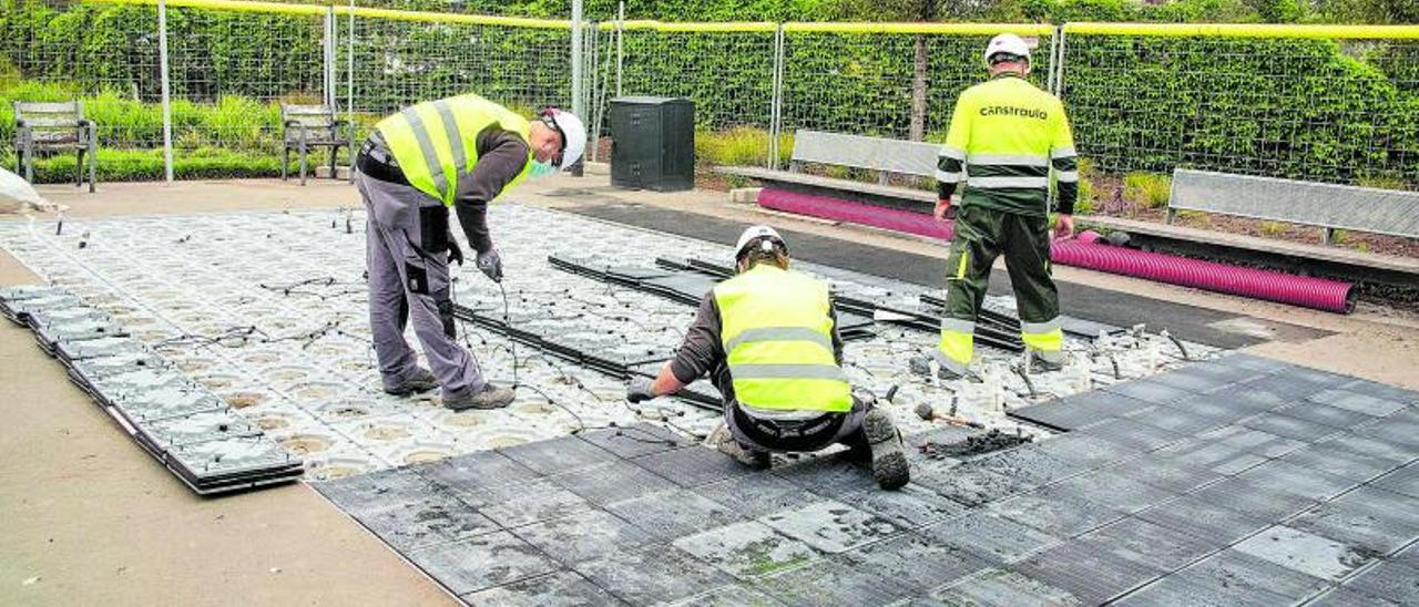 Unos operarios trabajan en la instalación del pavimento.