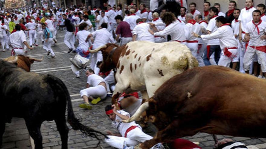 Varios mozos caen ante los toros de la ganadería salmantina de El Pilar en la curva de Mercaderes durante el séptimo encierro de los Sanfermines 2010.