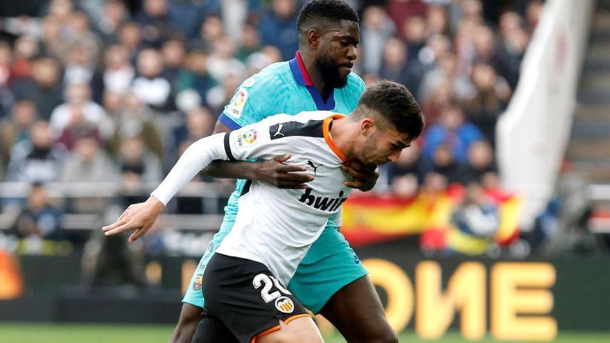 Samuel Umtiti (detrás) del Barcelona, disputa el balón con el centrocampista Ferrán Torres del Valencia.