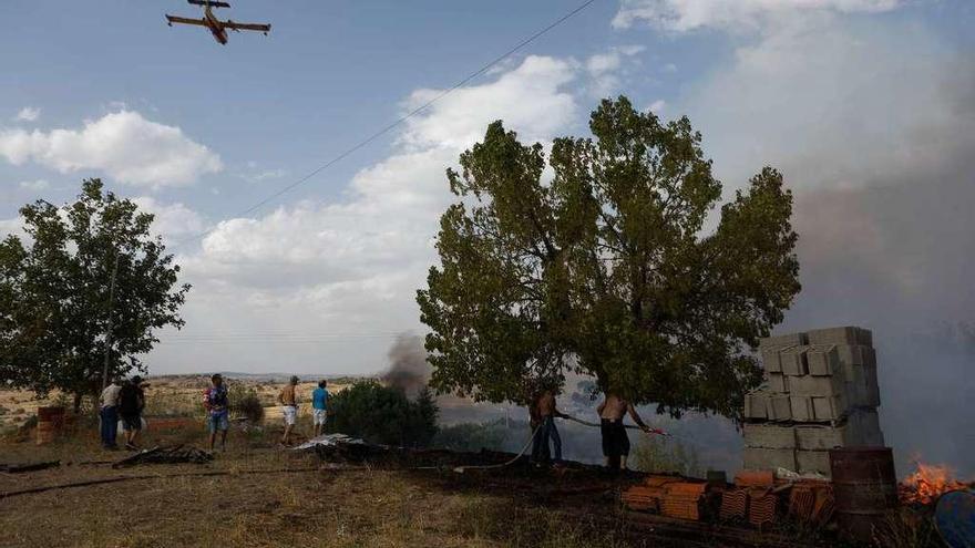 Un medio aéreo en la extinción del incendio de Fermoselle mientras los vecinos apagan con mangueras.