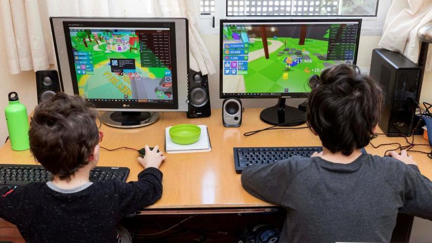 Dos niños juegan en sus ordenadores durante el confinamiento.