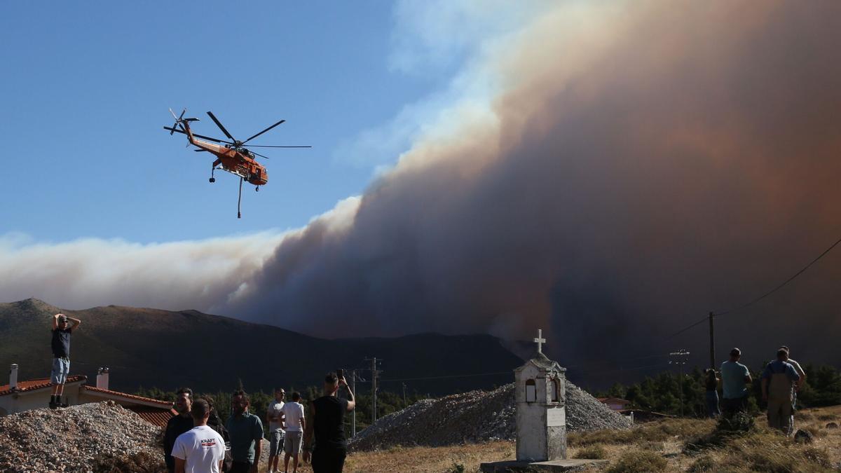 Desde Agios Nektarios, Viotia, la gente contempla el helicóptero que lucha contra el fuego en Porto Germeno.