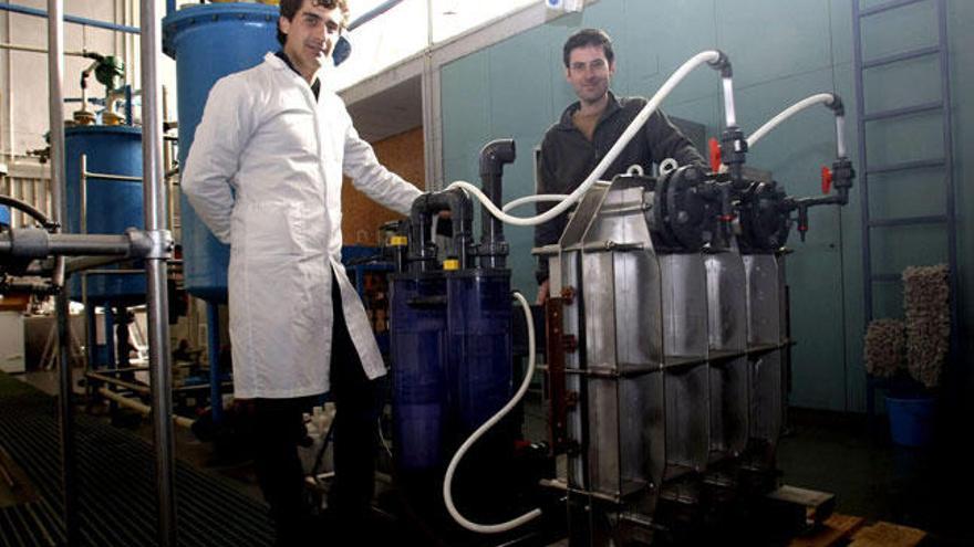 Los investigadores del Instituto Universitario de Electroquímica de la Universidad de Alicante (UA), Víctor José Climent (d) y Juan Manuel Ortiz, posan junto a un prototipo de pila microbiana para uso industrial que genera de forma simultánea energía y depura aguas residuales