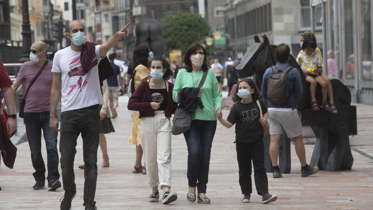 Asturianos con mascarillas por la plaza de